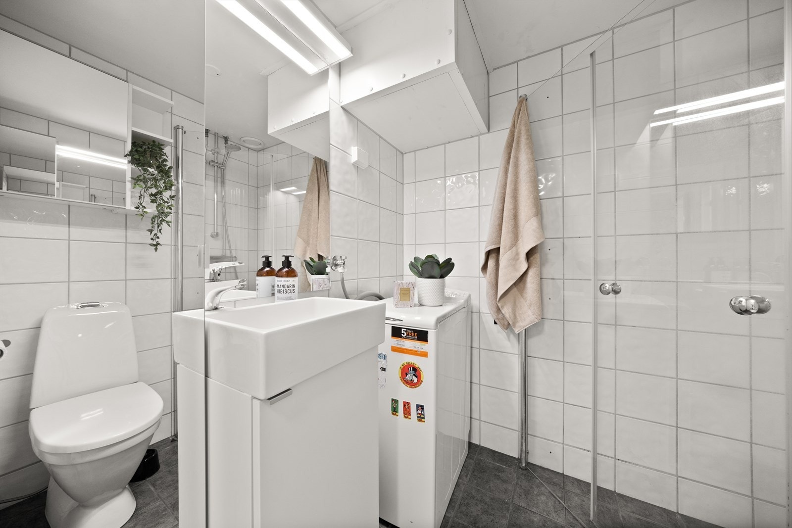 Badet er utstyrt med servant med underskap, dusjhjørne, toalett og opplegg for vaskemaskin Galleribilde