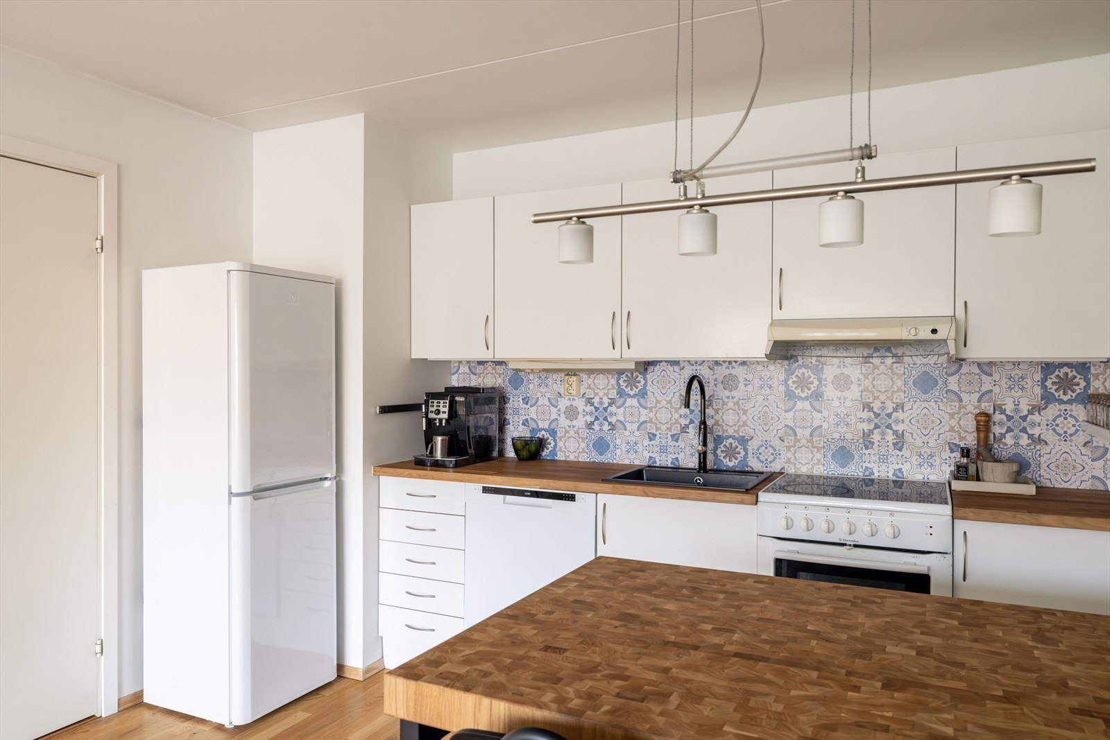 Mellom benkeskap og overskap er det montert en dekorativ folie med flismønster. Galleribilde