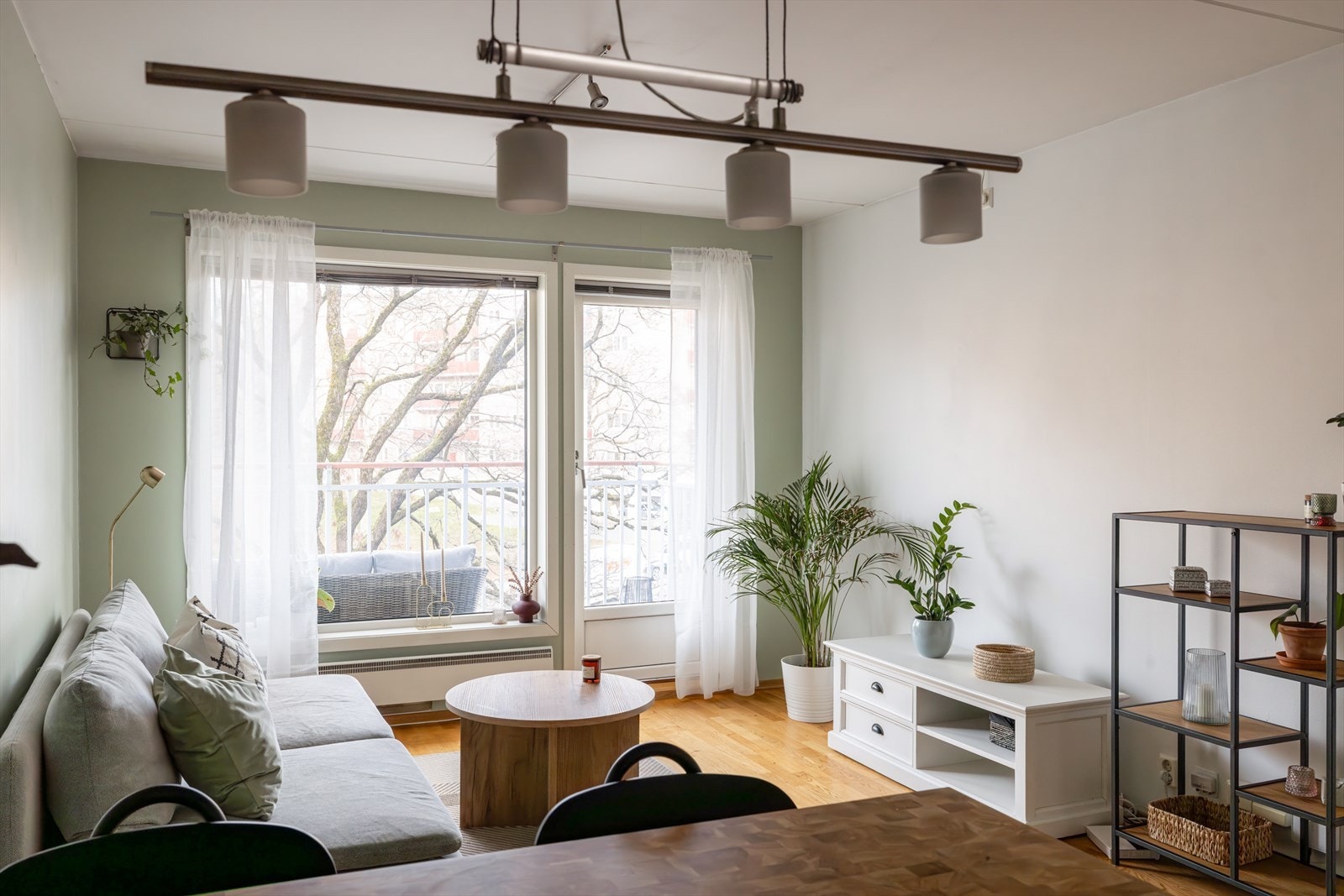 Stuen har et moderne uttrykk, med 3-stavs parkett på gulvet og vegger malt i en harmonisk lysegrønn nyanse, kombinert med en hvit kontrastvegg. Galleribilde