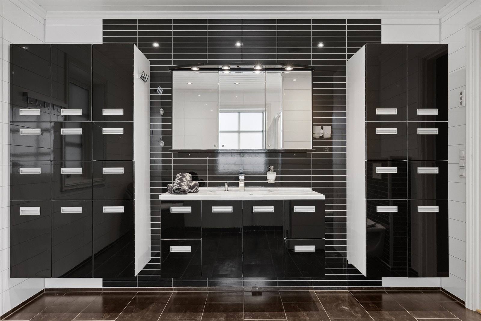 Badet har en stor innredning i sort utførelse med god plass til oppbevaring. Galleribilde