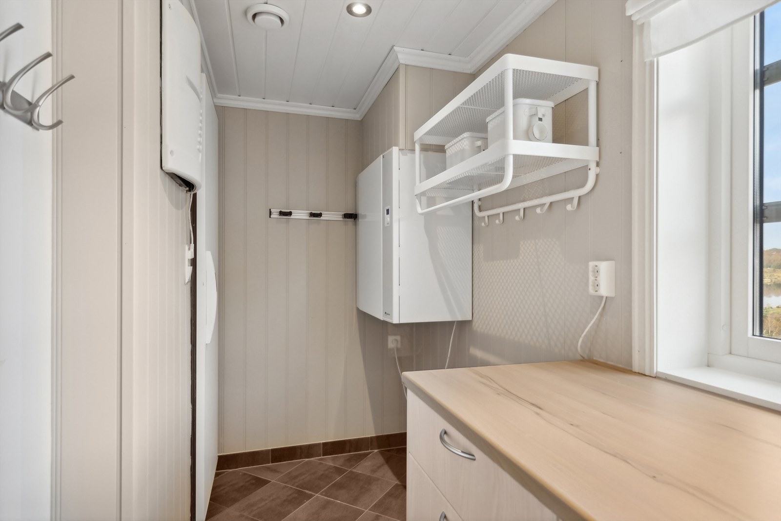 Separat vaskerom med fliser på gulvet og plater på veggene. Rommet har godt med plass i skap og skuffer. Galleribilde