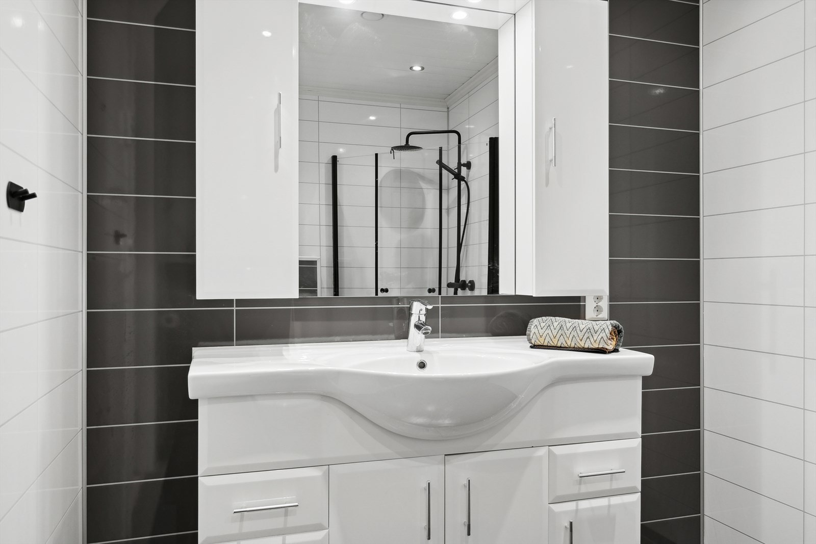 Badet inneholder vegghengt toalett, dusjhjørne med innfellbare dører og vask. Galleribilde