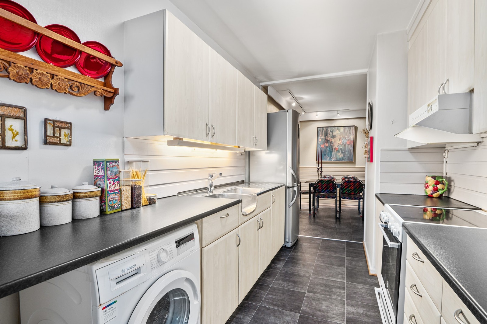 Kjøkkenet har innredning med opplegg for vaskemaskin og mekanisk avtrekksvifte over stekesonen. Galleribilde