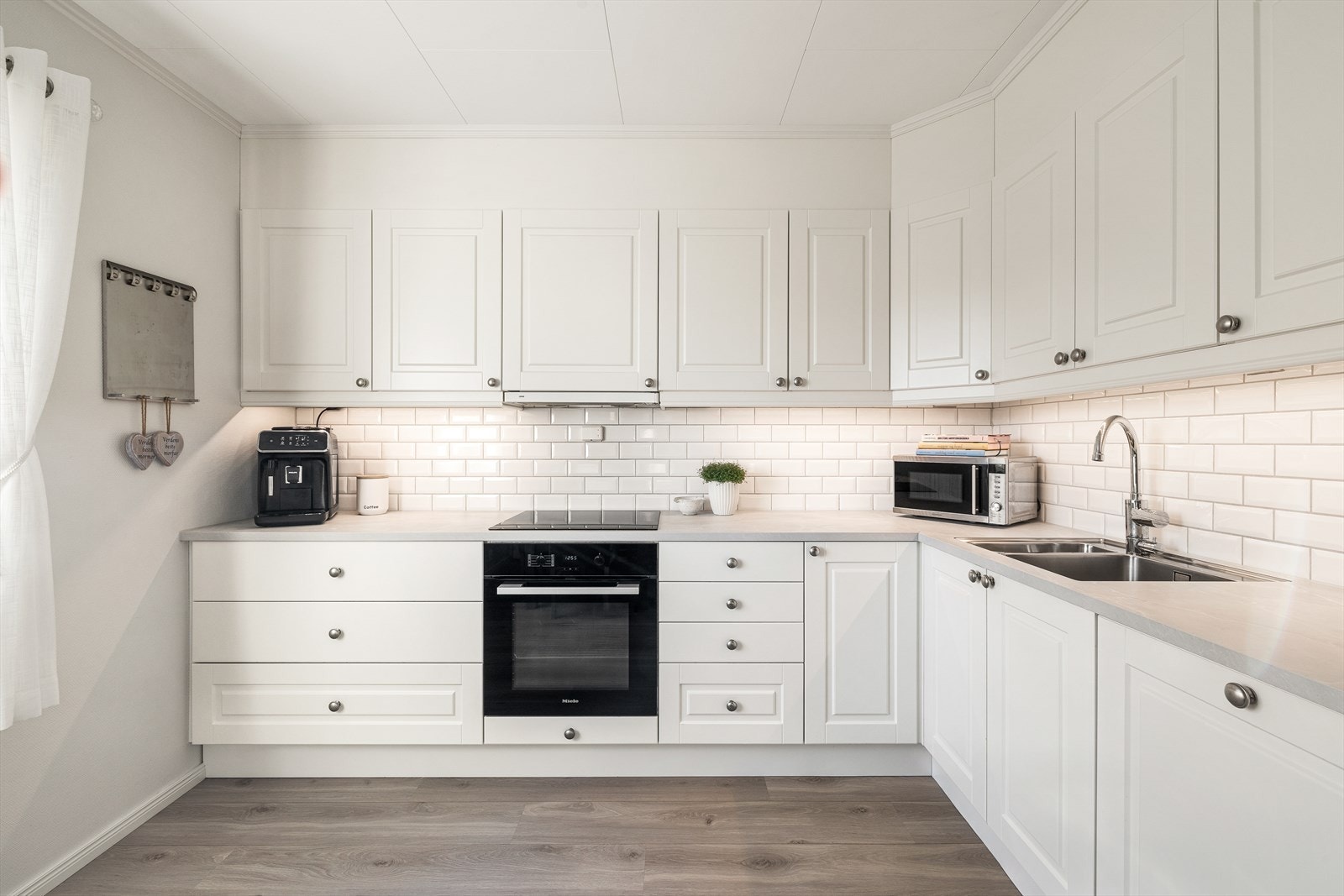Kjøkkenet har en stilren og klassisk innredning med laminat benkeplate med nedfelt benkebeslag og to kummer, samt delvis, integrerte hvitevarer. Galleribilde
