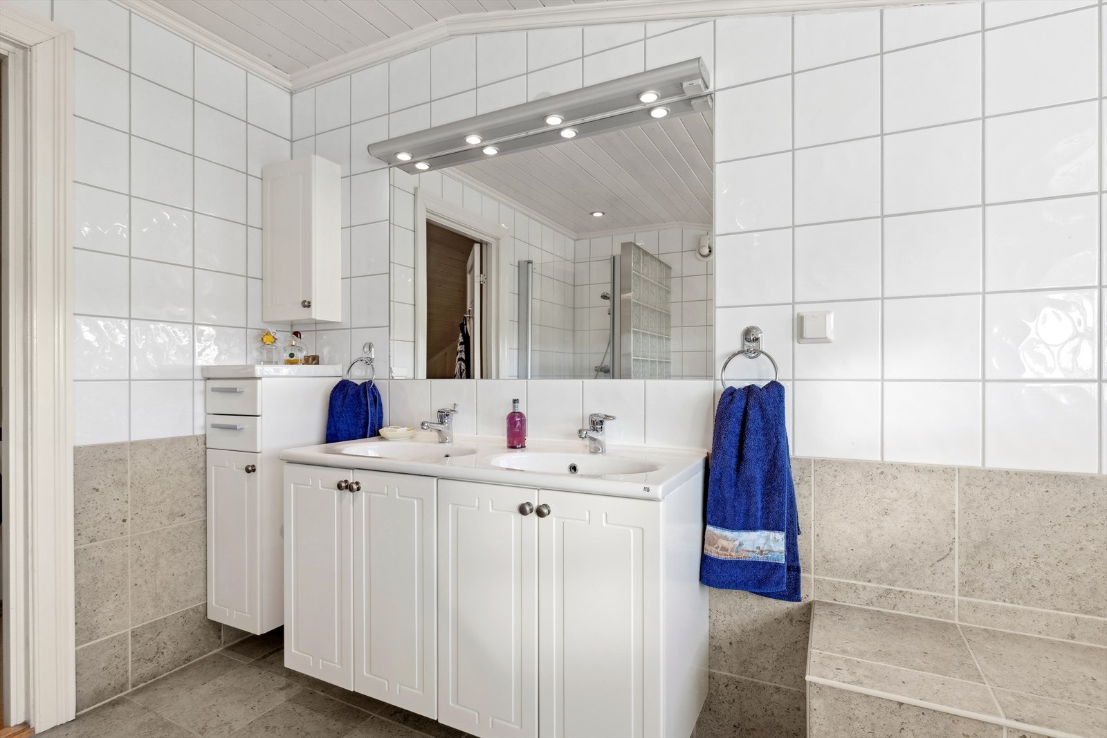 På badet er det hel servantplate med to servanter og servantskap, bidet, hjørnedusj med glassdør og glassbyggerstensvegg, flislagt badekar. Galleribilde