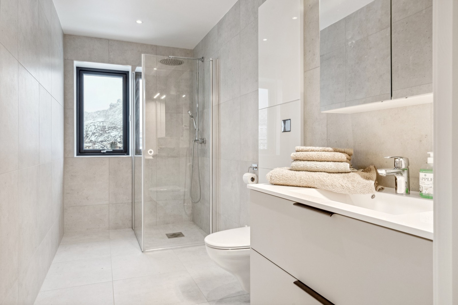 Bad 1 med vegghengt toalett, dusj, speilskap og servant. Her er det varme i gulv og downlights i taket. Galleribilde