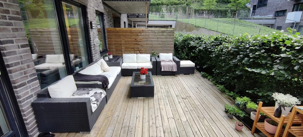 Fra stuen er det utgang til sydvendt markterrasse. Sommerbilde av markterrassen. Galleribilde