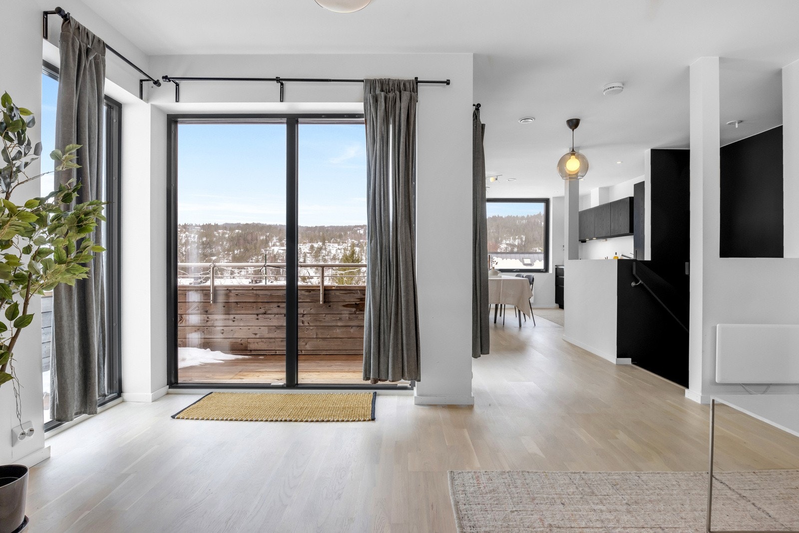 Stue og kjøkken i åpen løsning mes store vindusflater som slipper inn godt med naturlig lys. Galleribilde