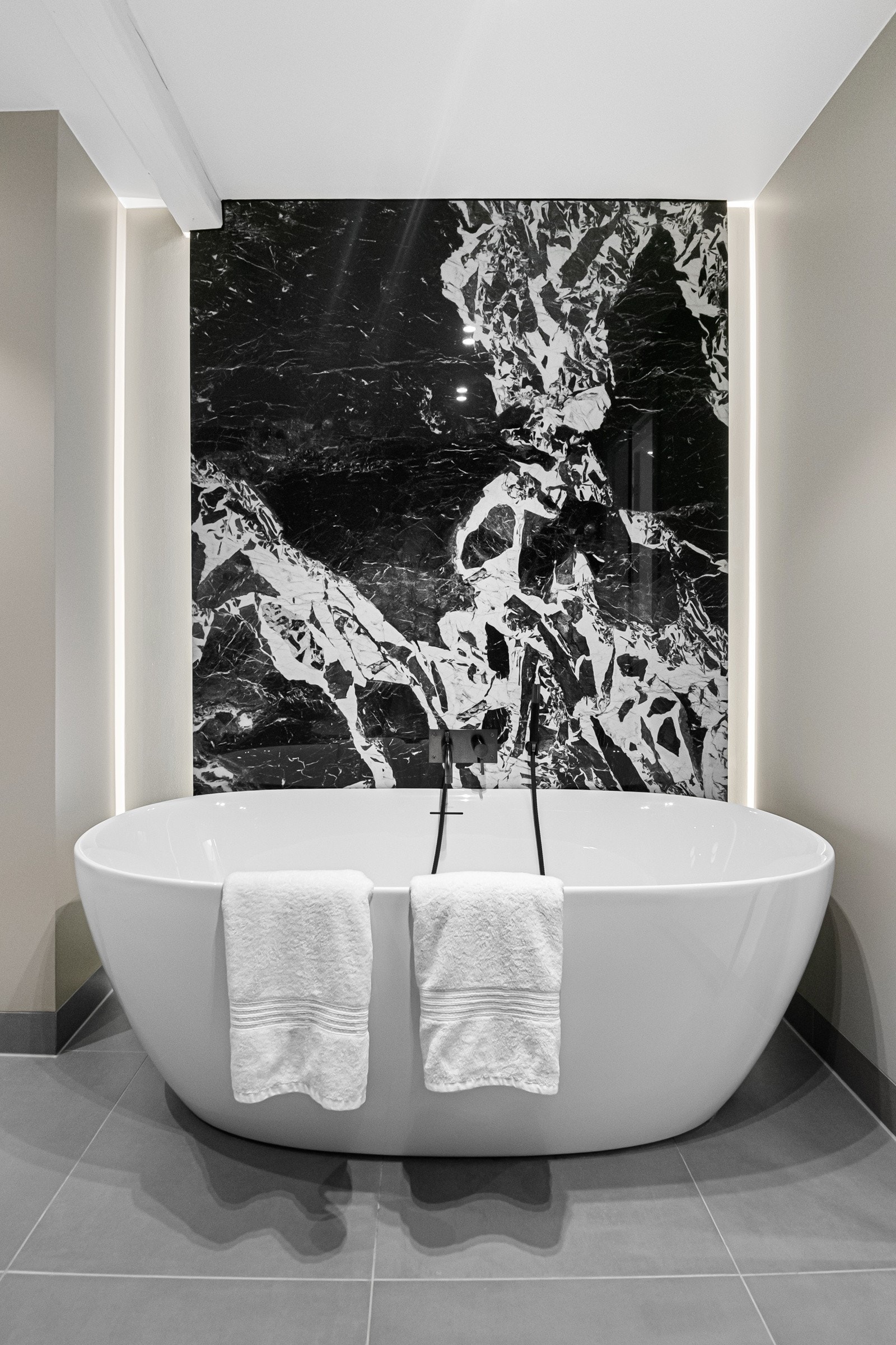 Designfliser fra Bergersen Flis, med integrert LED-belysning, gir badet et moderne og eksklusivt uttrykk. Hovedbaderommet er romslig og luksuriøst innredet, med både badekar og dusj for maksimal komfort Galleribilde