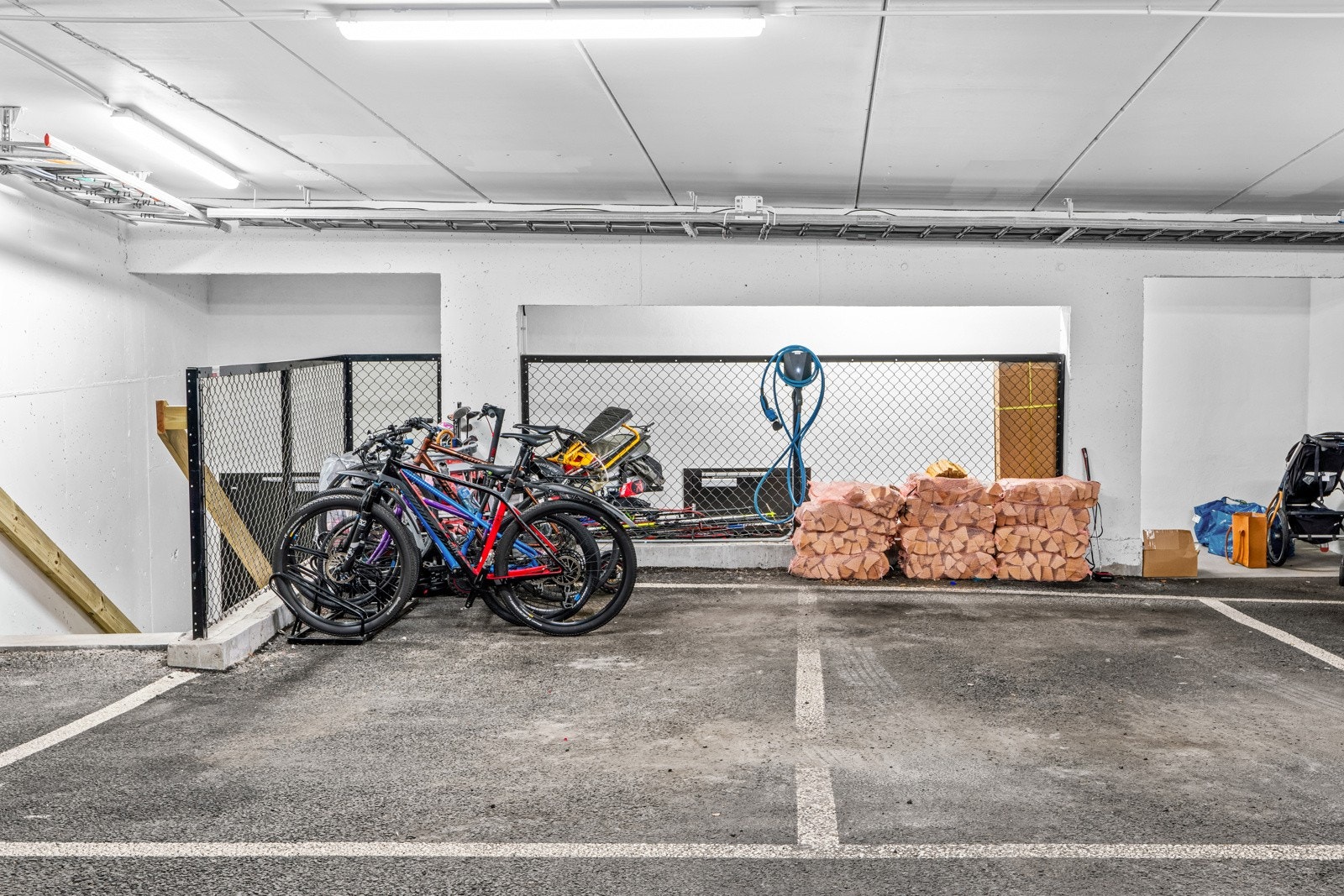 To parkeringsplasser i felles lukket garasjeanlegg med direkte adkomst til huset. Det er el-bil lader installert på en av plassene. Galleribilde