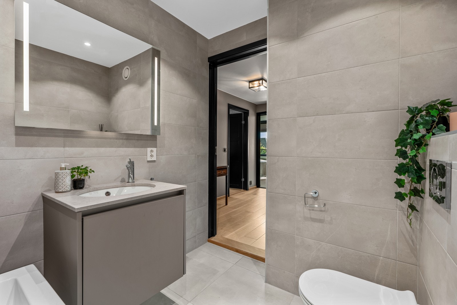 Badet er utstyrt med veggmontert toalett og praktisk badekar. Det er montert regnfallsdusj og det er laget dusjhjørne som kan byttes ut med badekaret om ønskelig. Galleribilde