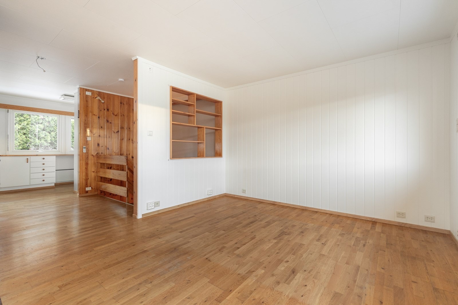 Stuen har parkett på gulv som er gjennomgående videre til gang og kjøkken, som gir en fin helhet. Vegger har panel og hvitmalt mdf-panel og det er hvite tak-ess i himling. Galleribilde