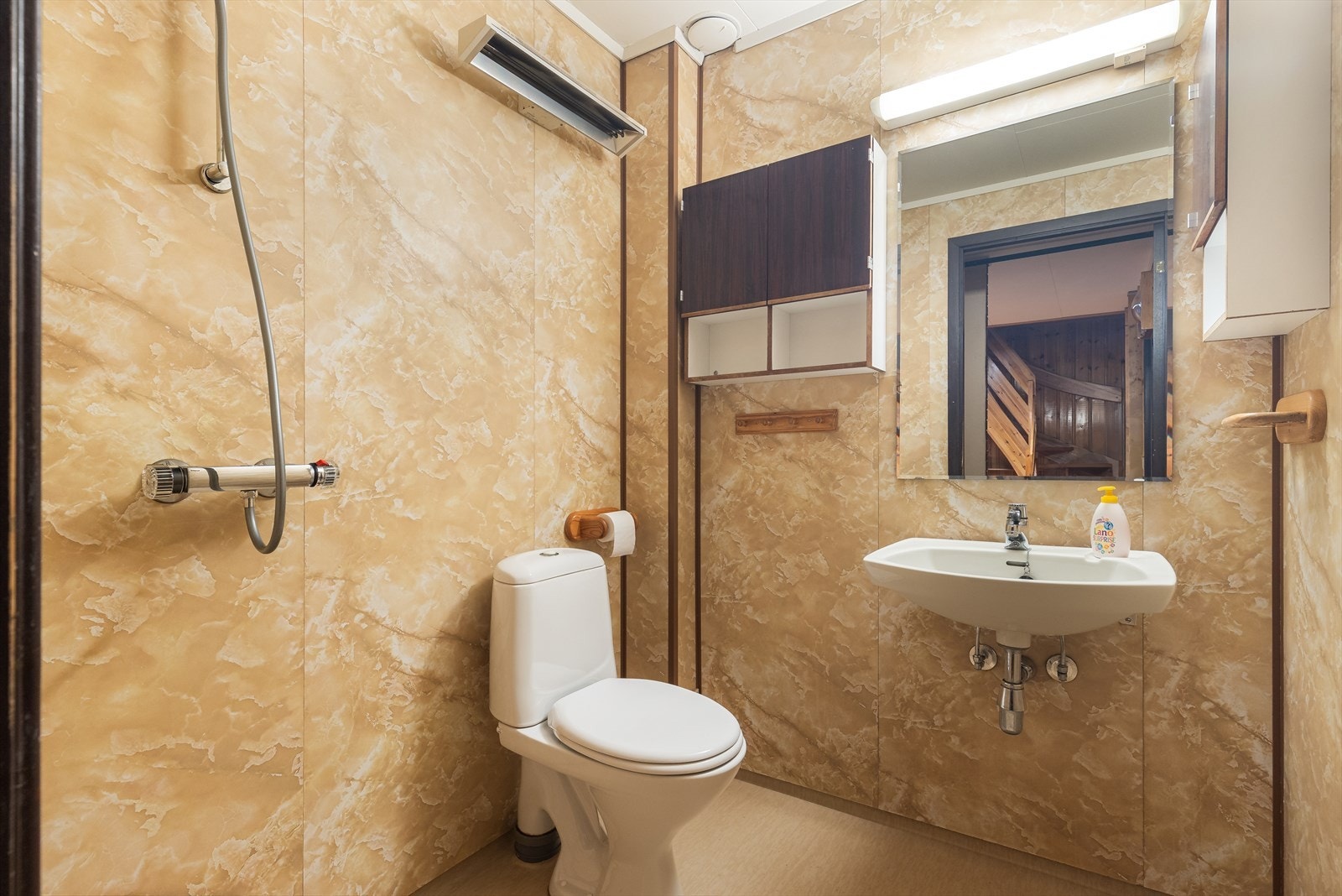 Underetasjen har også et eldre baderom hvor det er vinylbelegg på gulv, baderomspanel på vegger og tak-ess plater i himling. Innredning med servant på vegg, speil og lys over servant samt vegghengte skaper. Åpen dusjnisje med armatur på vegg og gulvmonter Galleribilde