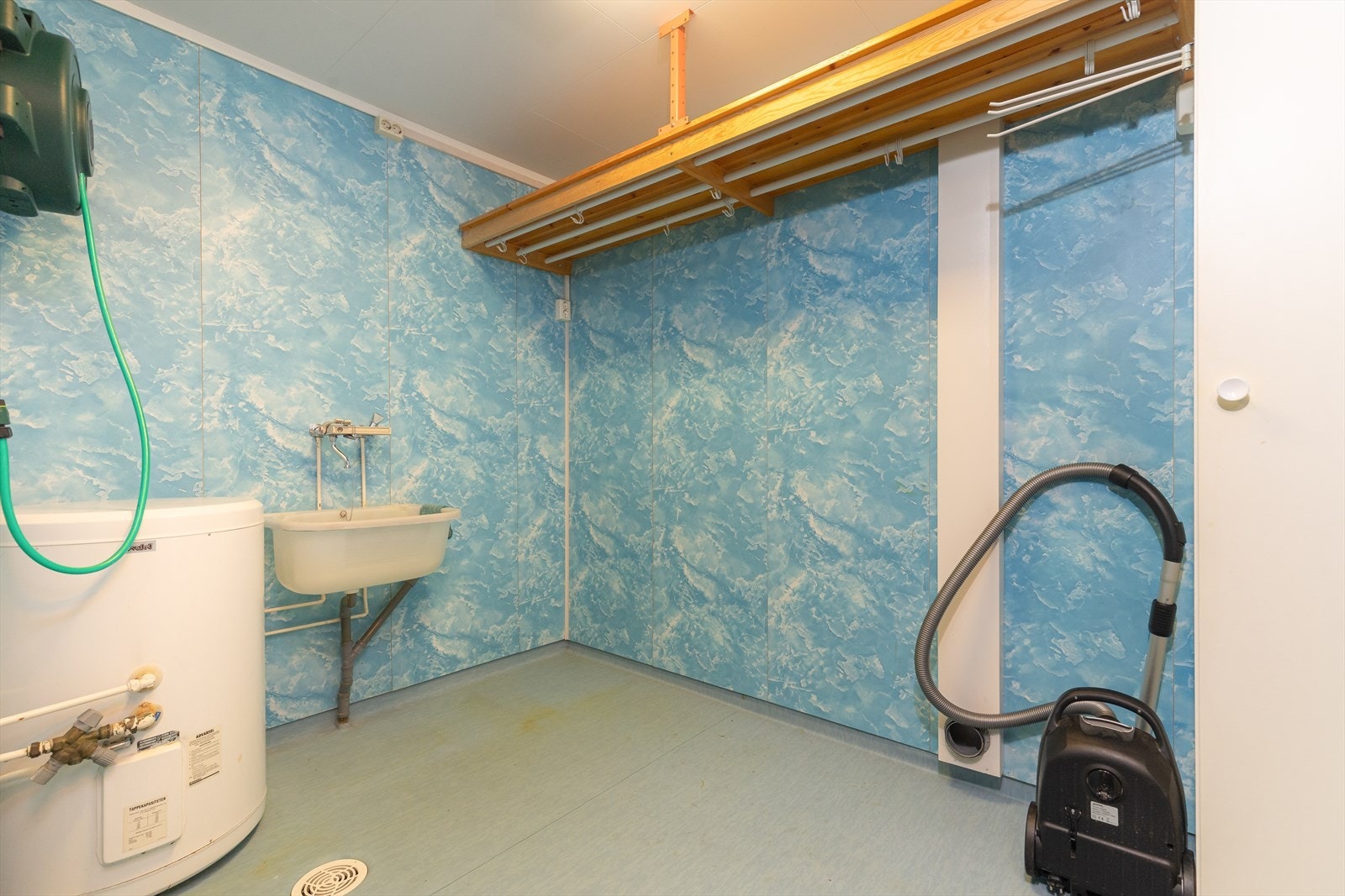 Vegg i vegg med badet er det et eldre vaskerom med vinylbelegg på gulv, baderomsplater på vegger og tak-ess plater i himling. Her er det vaskekum i pvc og opplegg for vaskemaskin. I tillegg er boligens varmtvannstank på ca. 120 liter plassert i rommet. Galleribilde