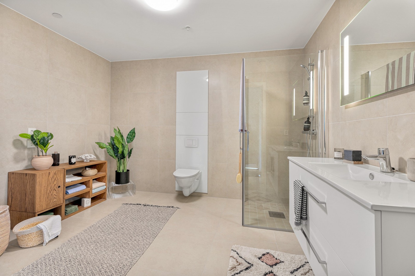 Det helflislagte badet kombinerer funksjonalitet med moderne stil. Med fliser på både gulv og vegger, vannbåren gulvvarme og smakfull innredning, er dette et rom som inviterer til velvære. Galleribilde