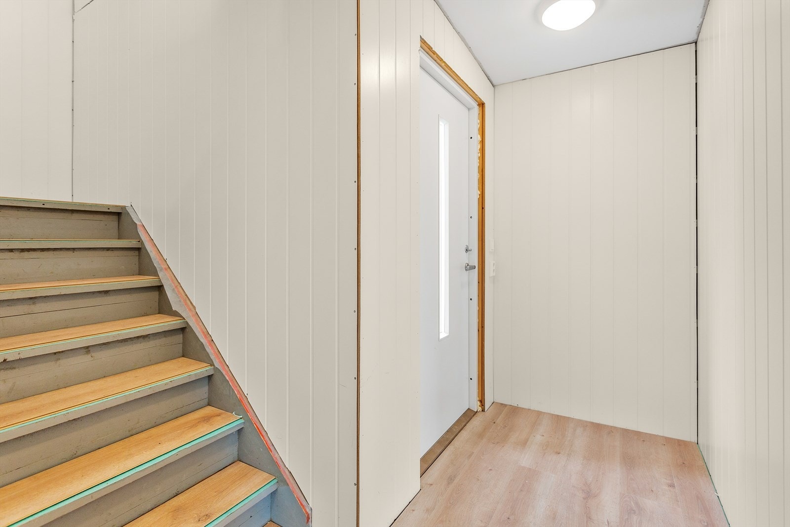 Lys entré med en-stavs gulv og trepanel på vegger. Dette er gjennomgående i hele boligen som gir et rent og helhetlig uttrykk. Galleribilde