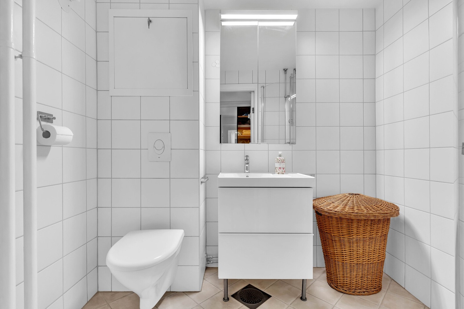 Baderommet har beige flislagt gulv med varme, hvite fliser på veggene, samt malt slett flate i himling. Baderommet er utstyrt med vegghengt servantinnredning, samt ovenpåliggende servant med ett-greps armatur. Galleribilde