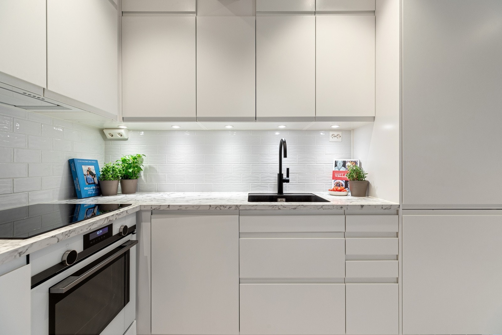 Lekker kjøkkeninnredning fra Sigdal med hvite grepsfrie fronter, overskap med benkebelysning og fliser på vegger Galleribilde