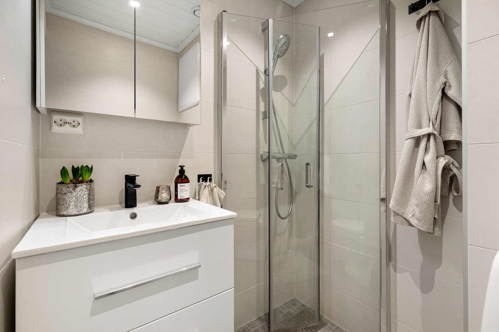 Flisalagt bad med varmekabler, dusjhjørne, veggmontert servantskap og klosett. Opplegg for vaskemaskin på kjøkkenet. Galleribilde