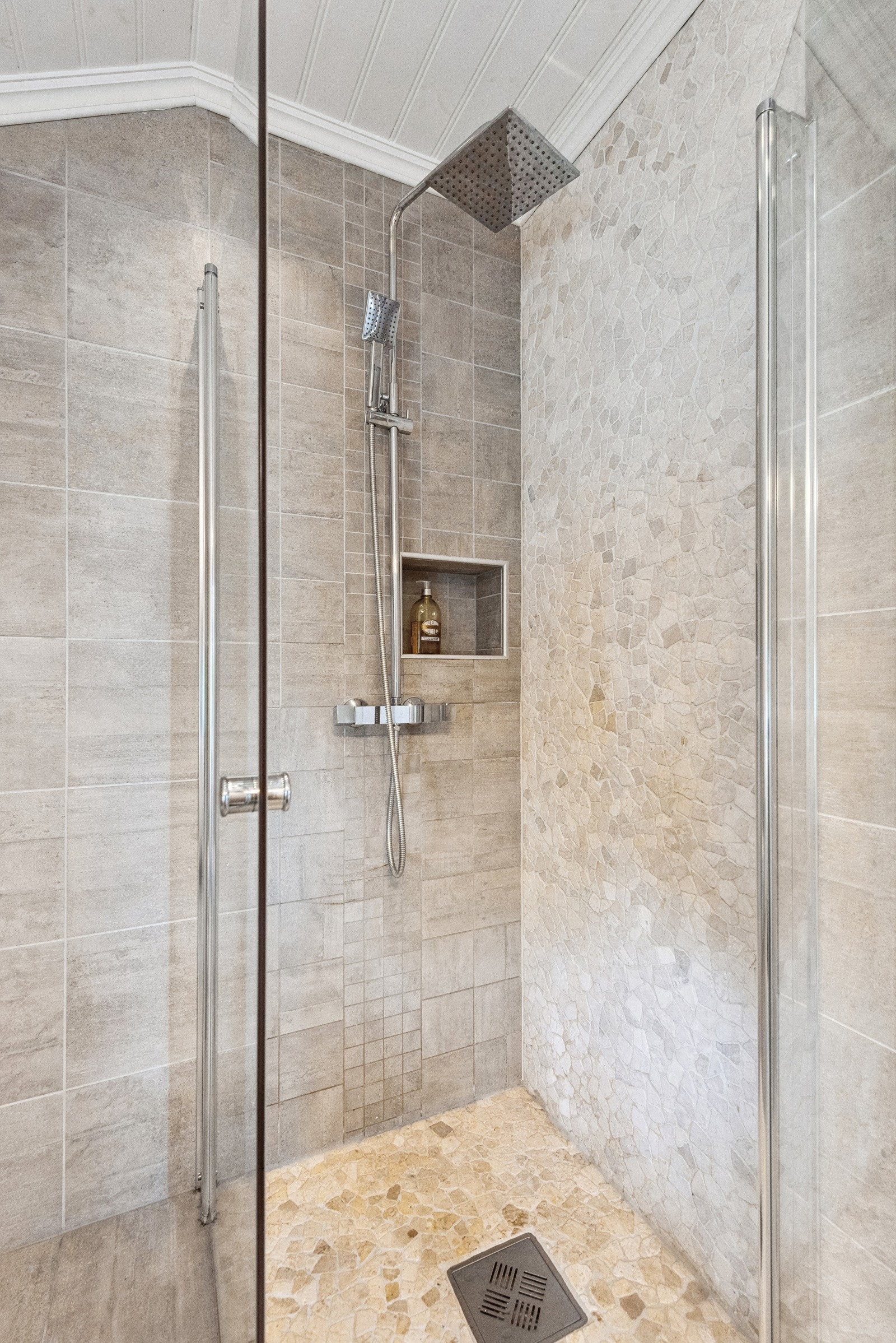 Badet har også dusjhjørne med innfellbare glassdører og regnfallsdusj. Såpe og shampo har egen innfelt nisje i veggen. Galleribilde