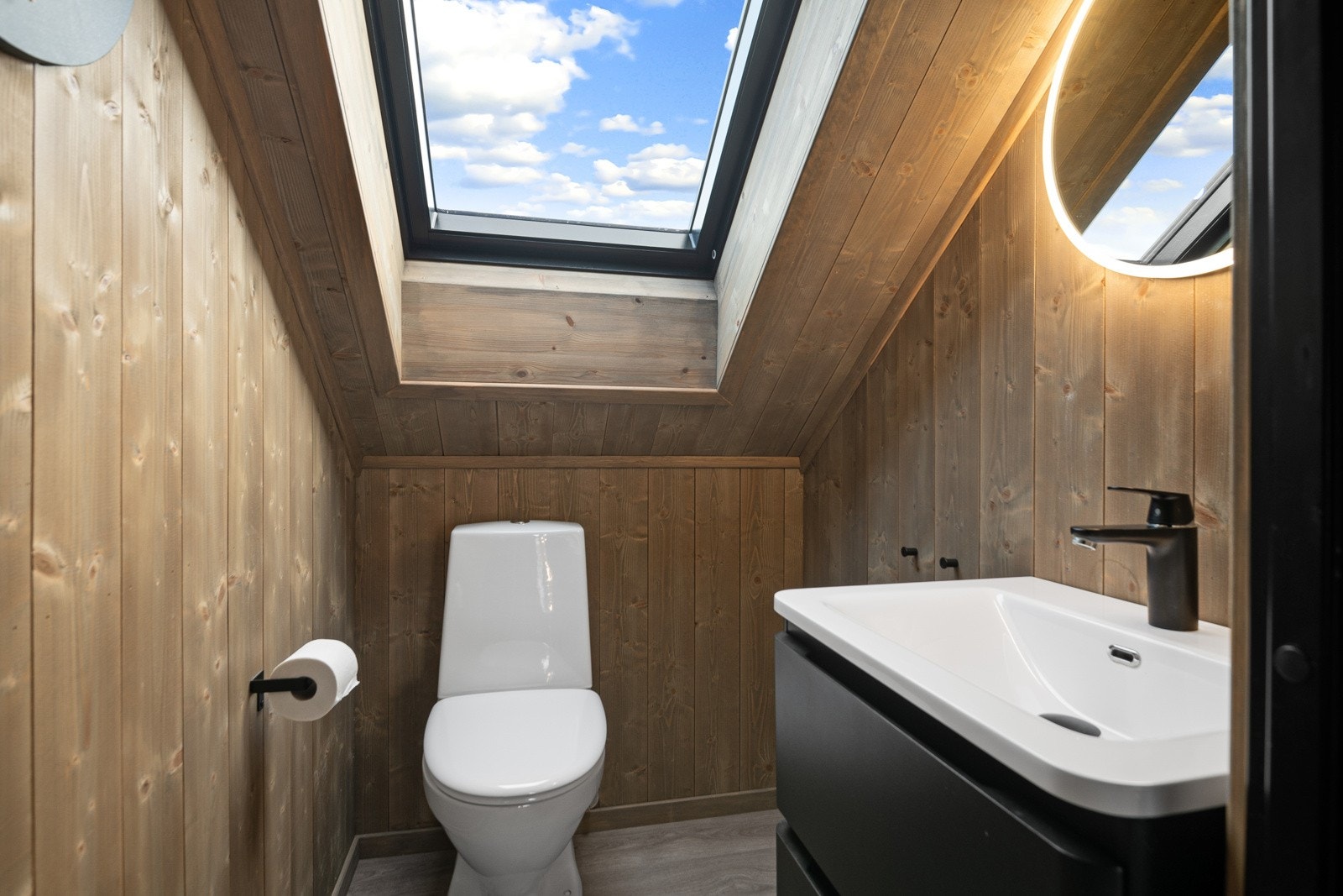 I annen etasje finnes også et praktisk toalettrom som inneholder baderomsmøbel med servant og lys med speil, samt toalett. Et stort takvindu gir godt med naturlig lys. Galleribilde