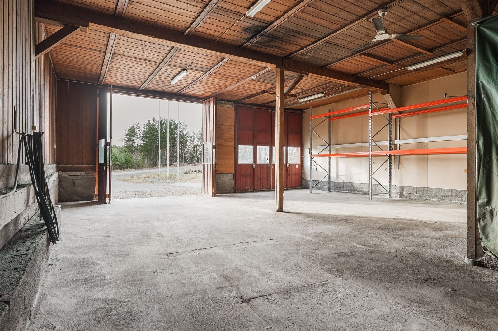 Garasje med betonggulv, vegger med bord/gips og himling med trebord. Intern ståltrapp ved garasje med åpne opptrinn og rekkverk. Galleribilde