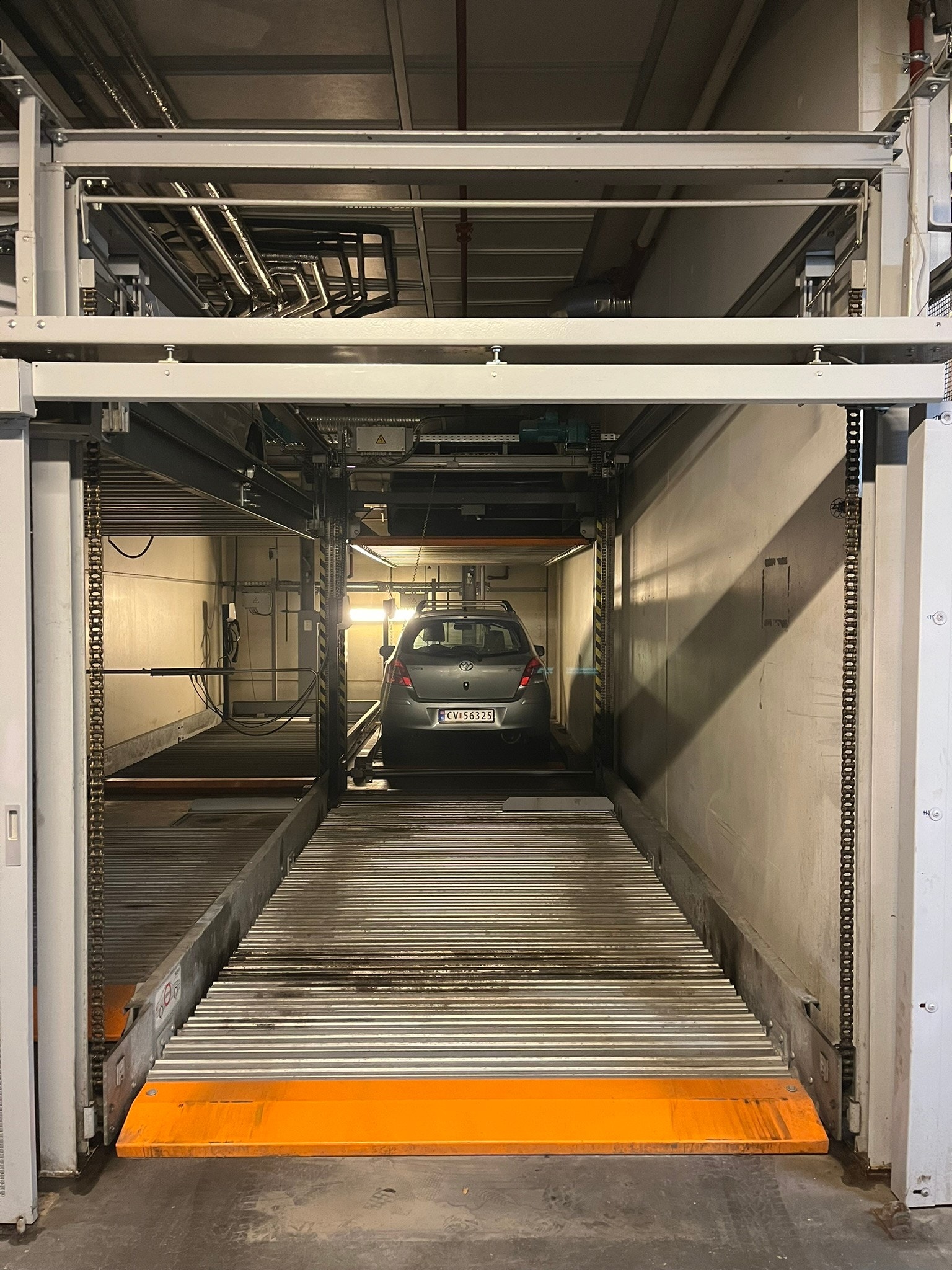 Plass ligger på 1 rad for en enkel innkjøring. Plattform heves når bil bak skal inn/ut. Galleribilde