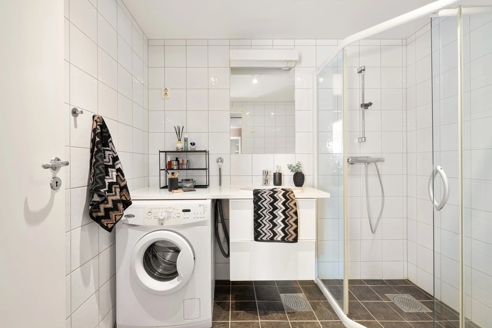 Badet har vegghengt baderomsmøbel med heldekkende servant, speil, vegghengt toalett og dusjhjørne. Galleribilde