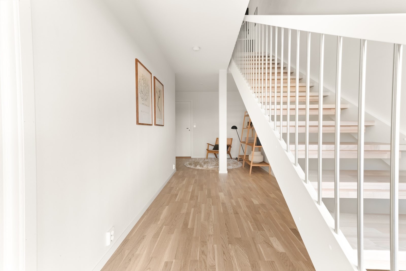 Det er åpen trapp i mellom etasjene med hvitmalte vanger og stolper, samt spiler i metall og trinn i lakkert eik. Galleribilde