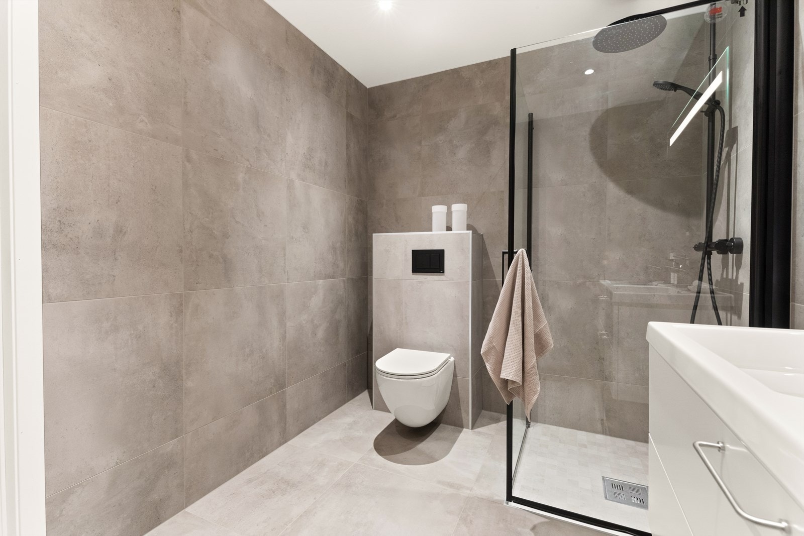 Baderomsinnredning fra Drømmekjøkkenet, vegghengt toalett med sisternehylle og dusjhjørne med innfellbare glassdører. Galleribilde