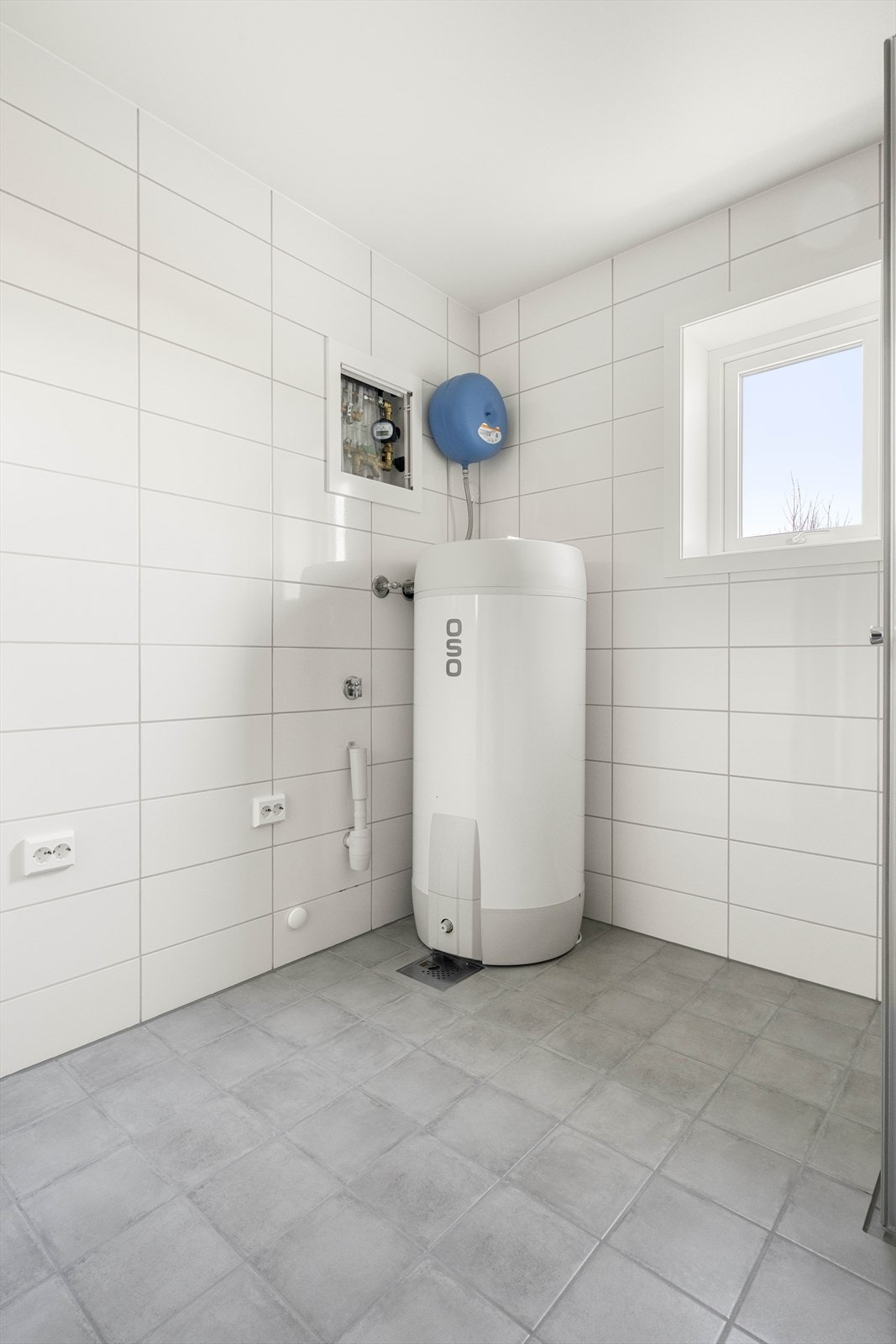 Varmtvannsbereder og plass til vaskemaskin og tørketrommel på badet Galleribilde