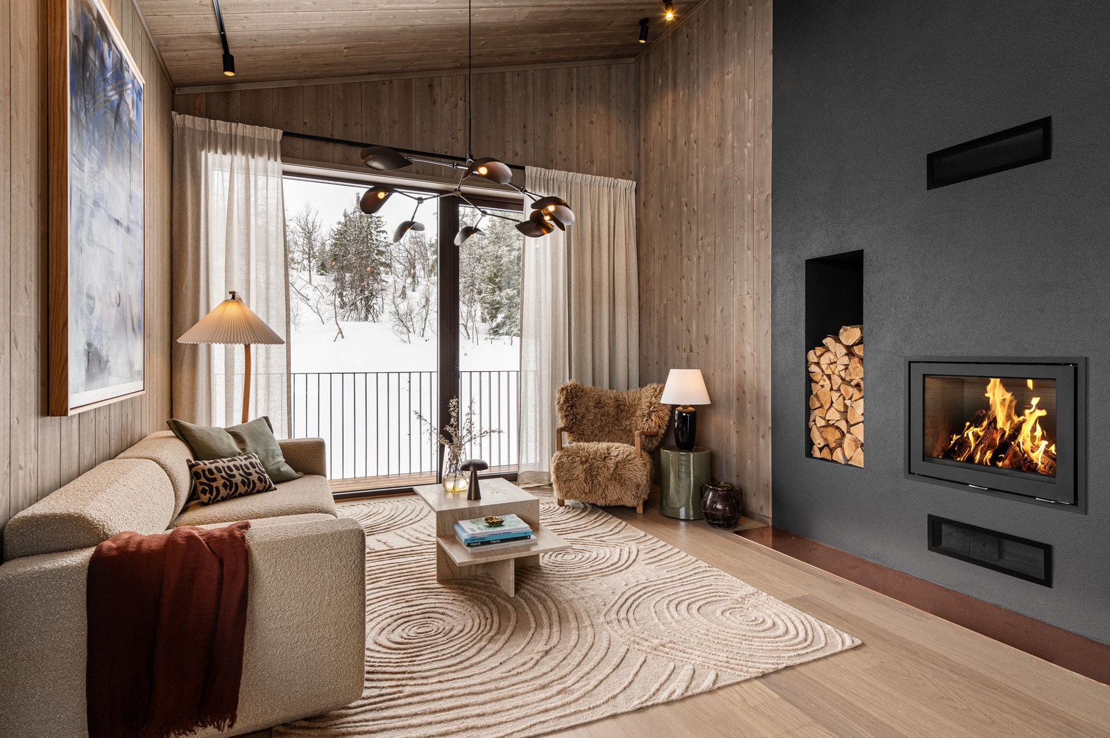 Foto av hytte 1B. En lys og varm stue på kalde vinterdager, med fantastisk utsikt, generøs takhøyde og rause vindusflater samt en stilfull peisinnsats fra Rais. Galleribilde