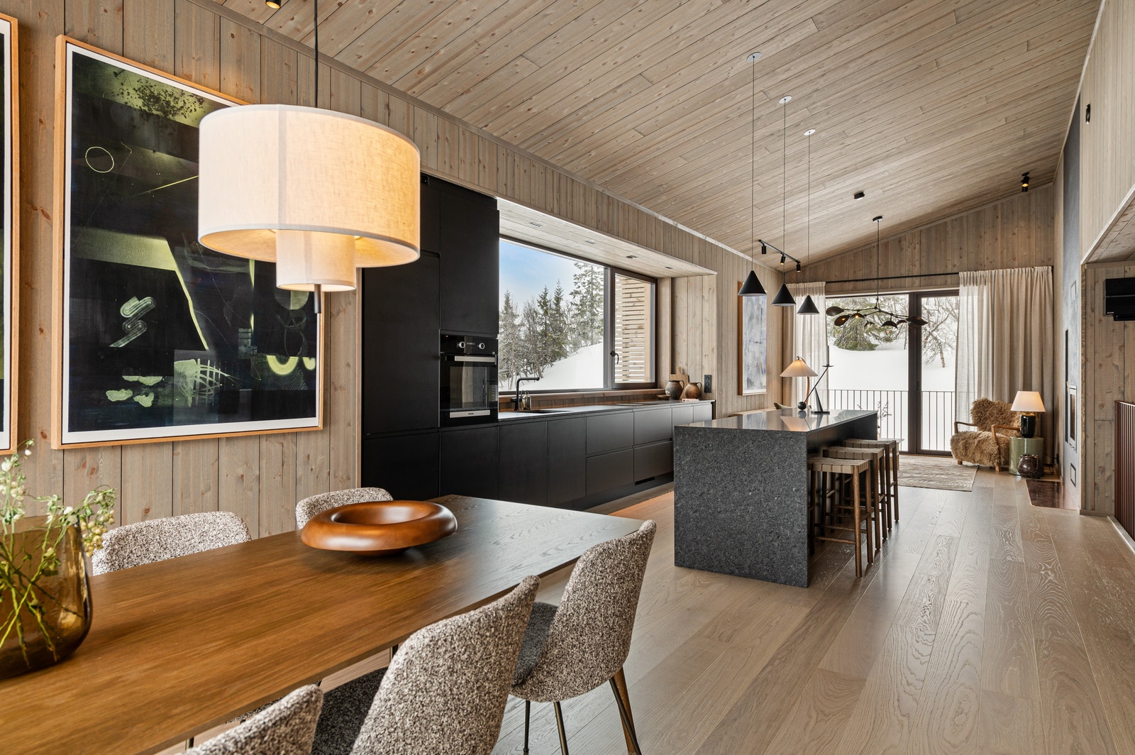 Foto av hytte 1B. Gjennomgående oppholdssone med takhøyde fra ca. 2,8 til 3,8 meter. Store vindusflater og balkong i begge ender. Galleribilde