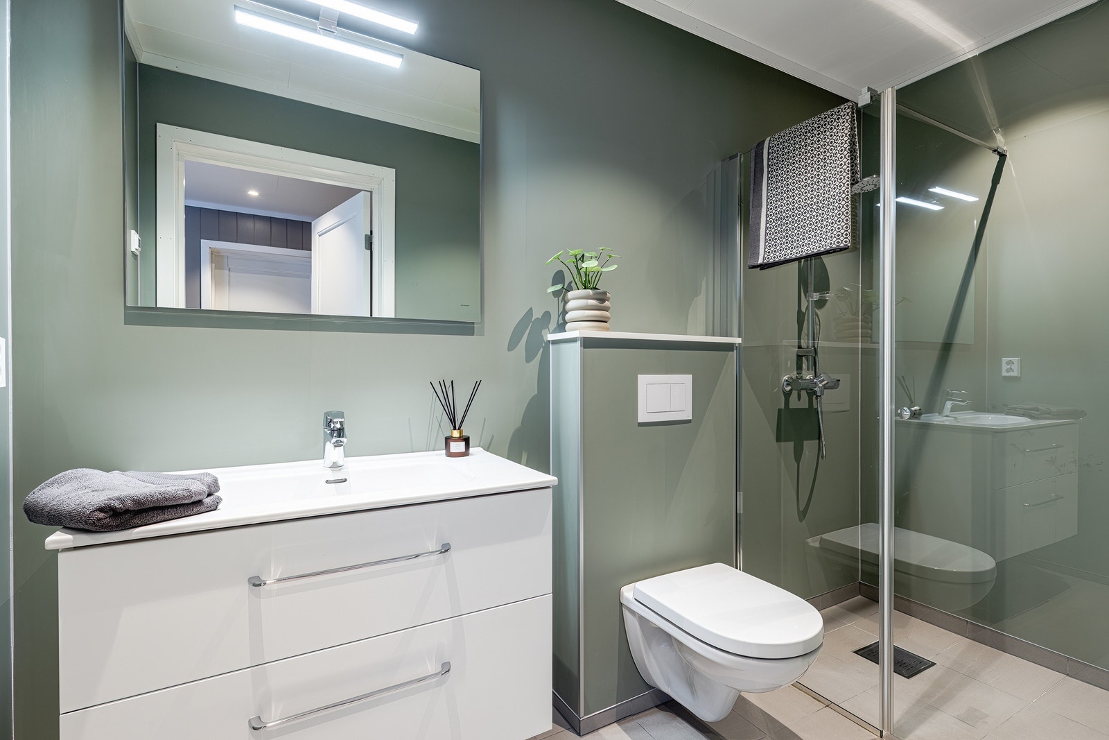 I hovedetasjen finner du også et mindre bad med romslig dusjhjørne, vegghengt toalett og baderomsinnredning med skuffer og heldekkende servant. Galleribilde