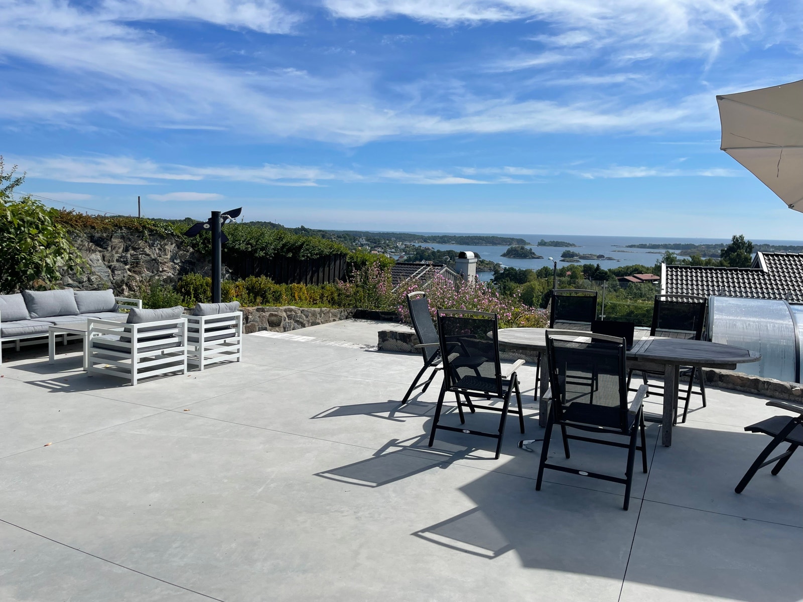 Stor terrasse i betong og tre med sittegrupper. Galleribilde