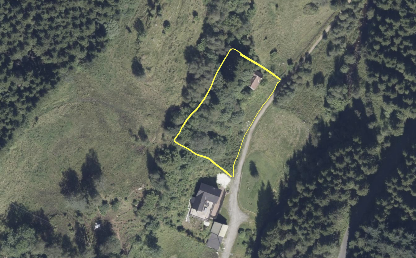 Flyfoto av tomten. Tomtegrense er skissert på frihånd etter hukommelsen i gult. Gå til NorgesKart for nøyaktig grense. Det gamle huset kan sees i nord på tomten. Det nye bygget er søkt om nærmere senter av tomten. Galleribilde