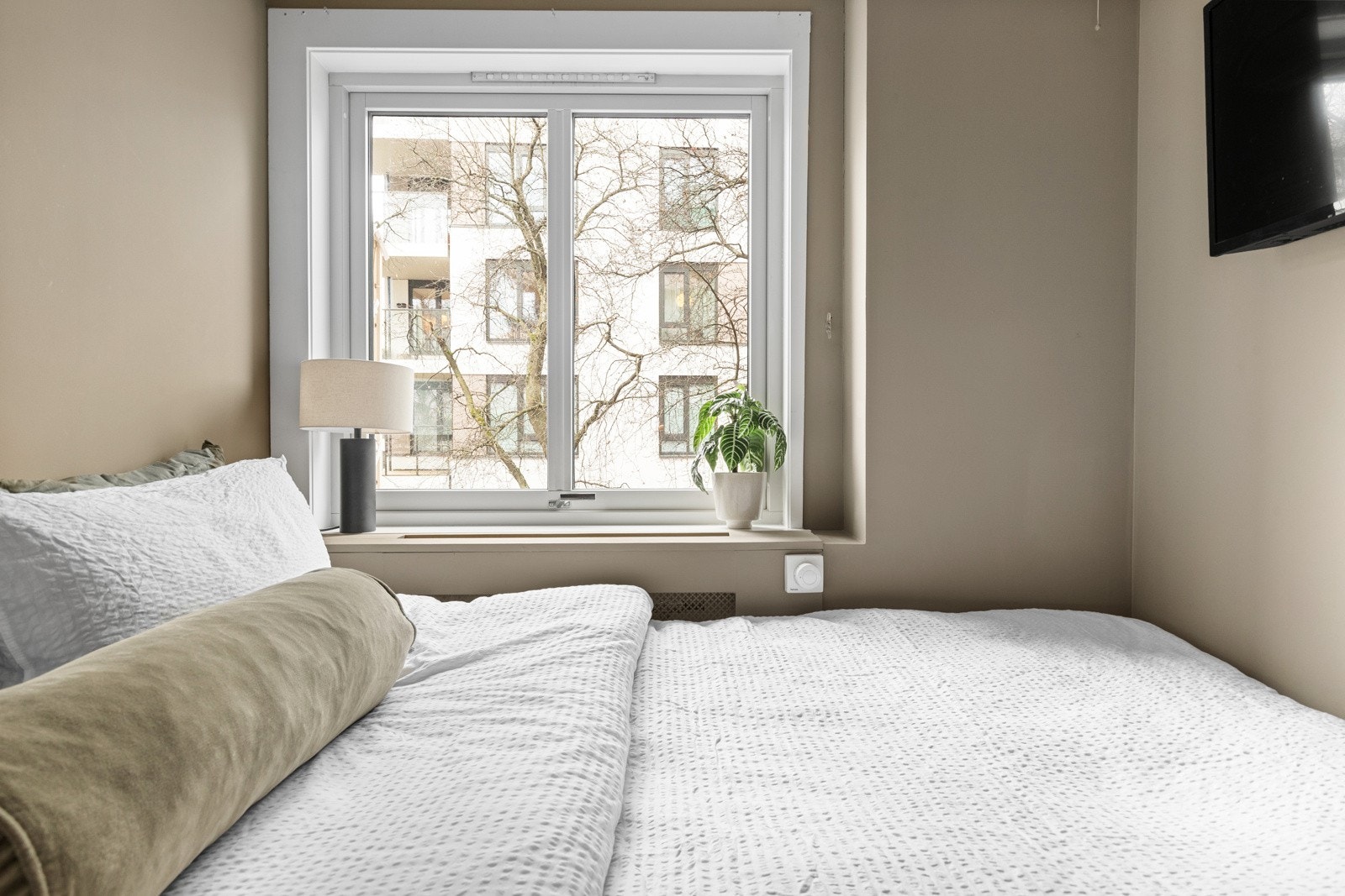 Stor vindusflate sørger for naturlig lysinnslipp. Soverommet er også malt i en flott beige farge som skaper en lun atmosfære gjennom alle årets sesonger. Galleribilde