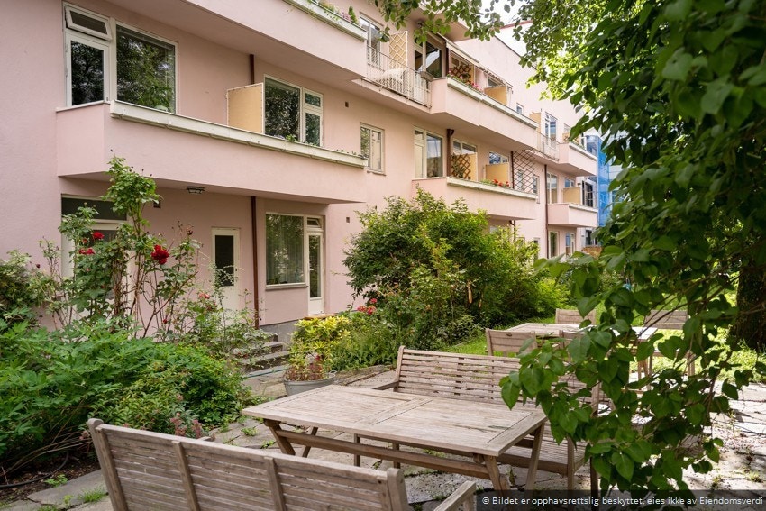 Hyggelig gårdsrom som er opparbeidet med beplanting, trær og gressplen. Galleribilde