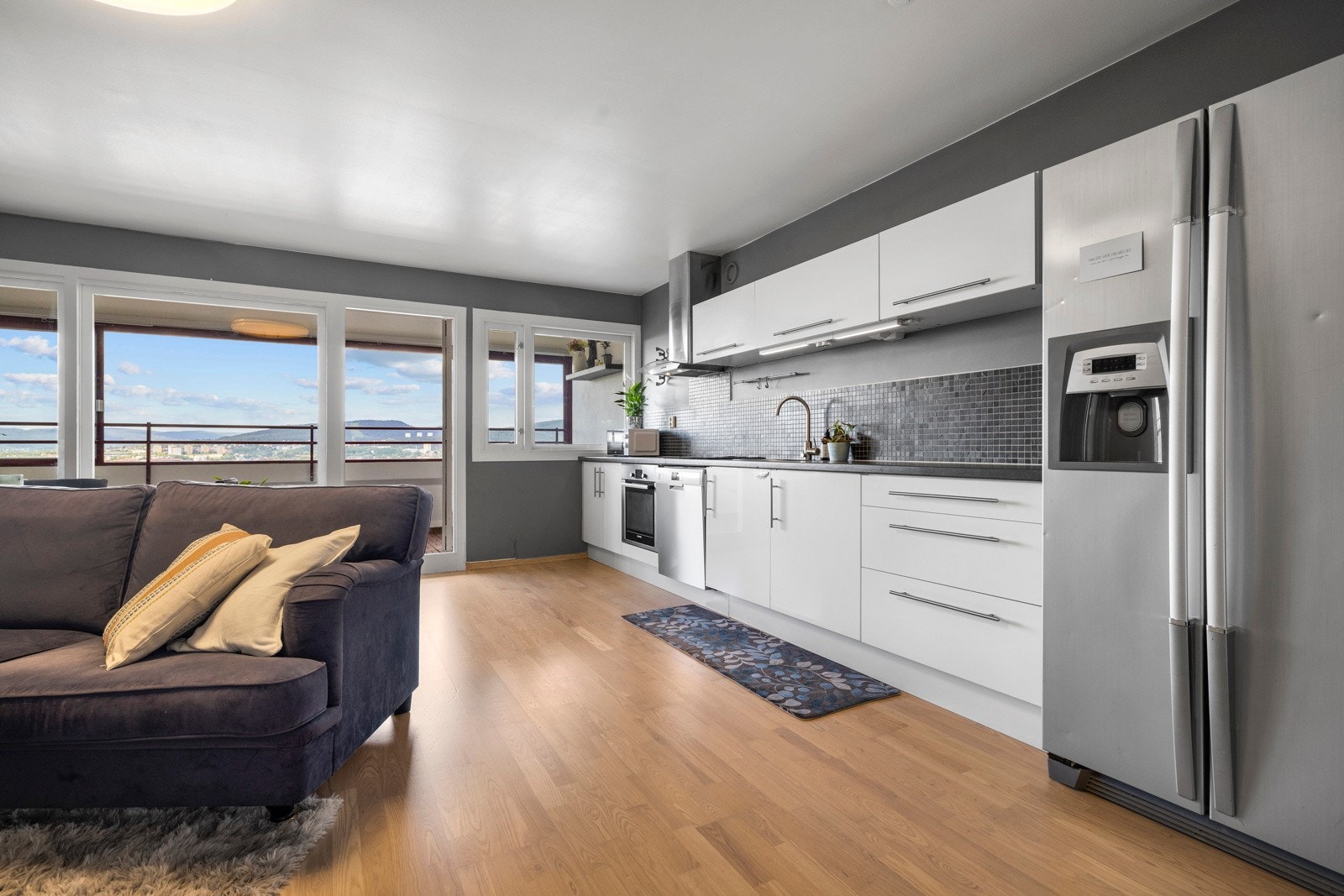 Kjøkkeninnredningen har benkeplate i laminat, oppvaskkum av stål, benkebelysning og mosaikkfliser over benken Galleribilde