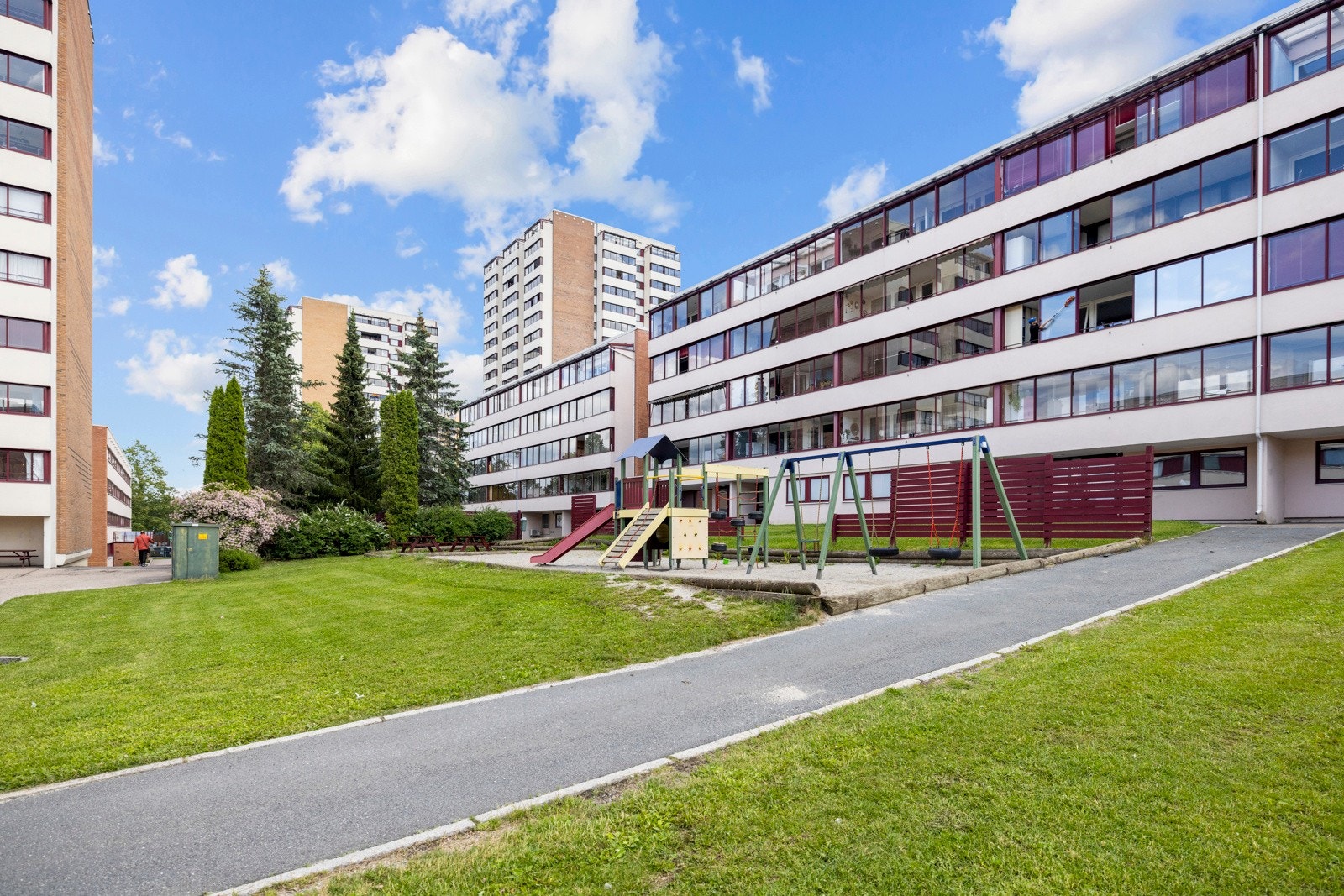 Blant det grønne er det sittebenker og lekeplass, og langs asfalterte gangveier er det sykkelstativ Galleribilde