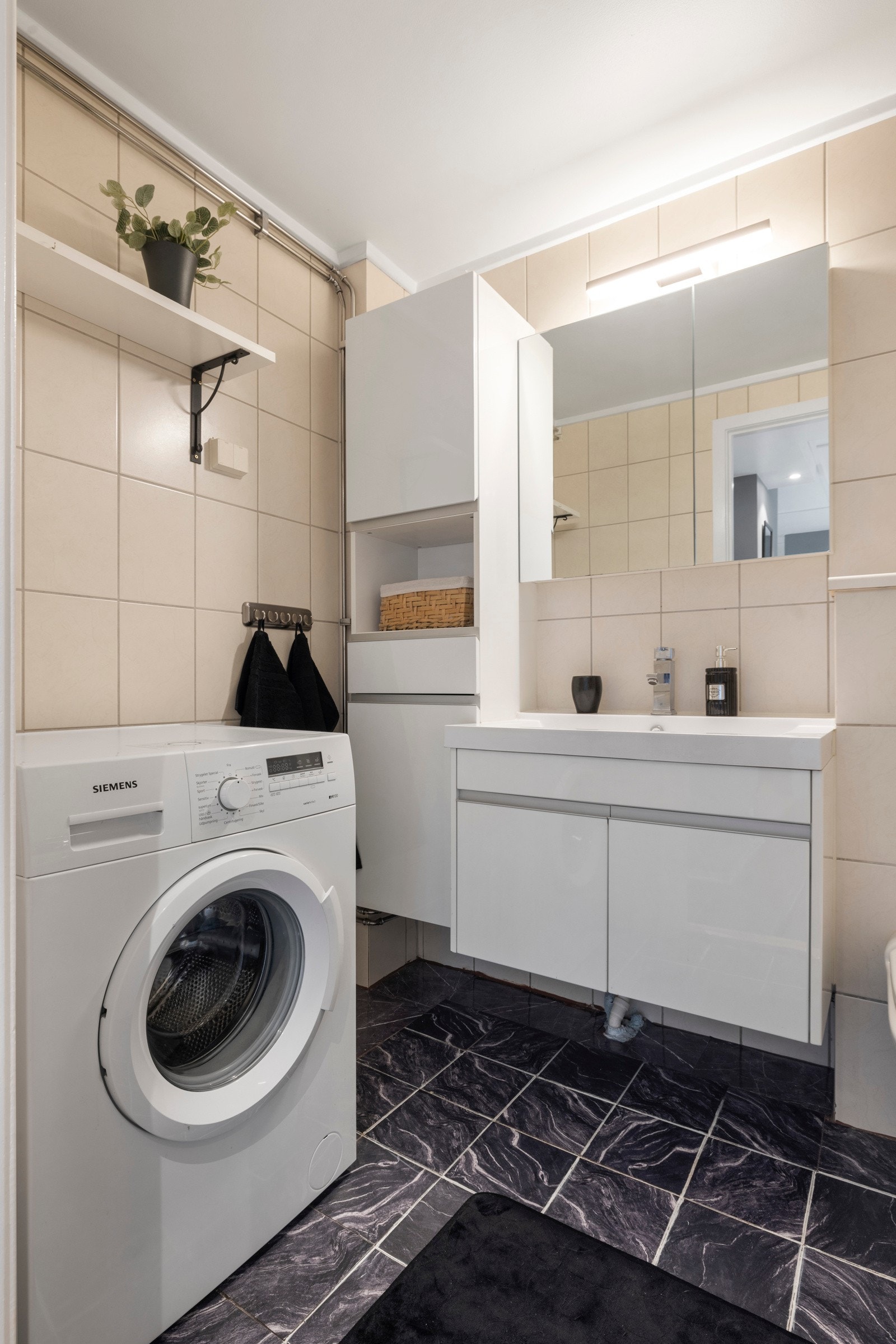 Badet har gulvvarme, vegghengt toalett, opplegg for vaskemaskin og et innfliset badekar med svingbar dusjvegg Galleribilde