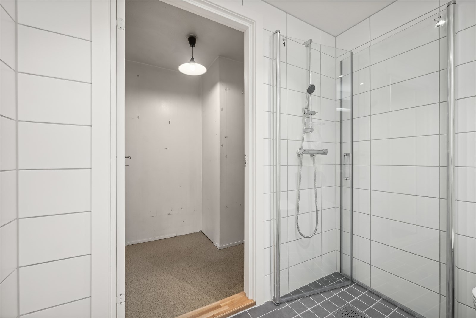 Rommet er ellers utstyrt med dusjhjørne med svingbare glassvegger, vegghengt toalett, servant med praktiske underskap og opplegg for både vaskemaskin og tørketrommel. Galleribilde