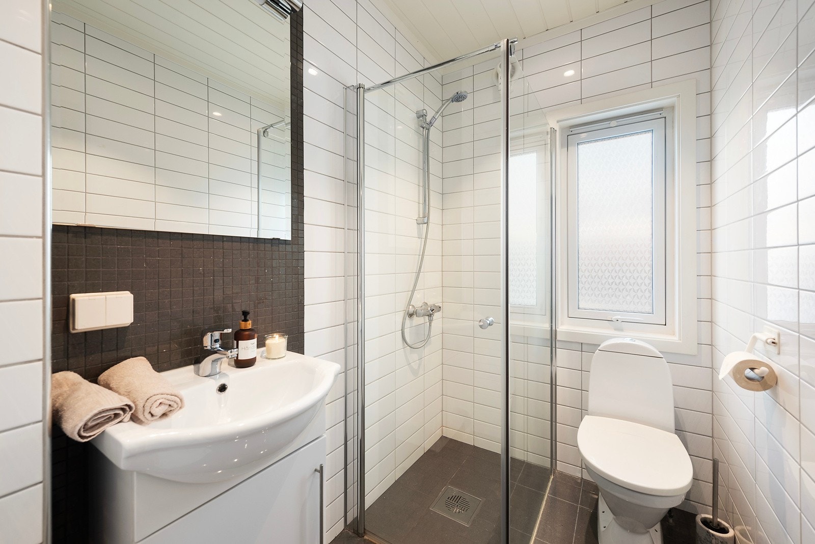 Badet er praktisk innredet med servantinnredning med skap, toalett og dusjhjørne Galleribilde