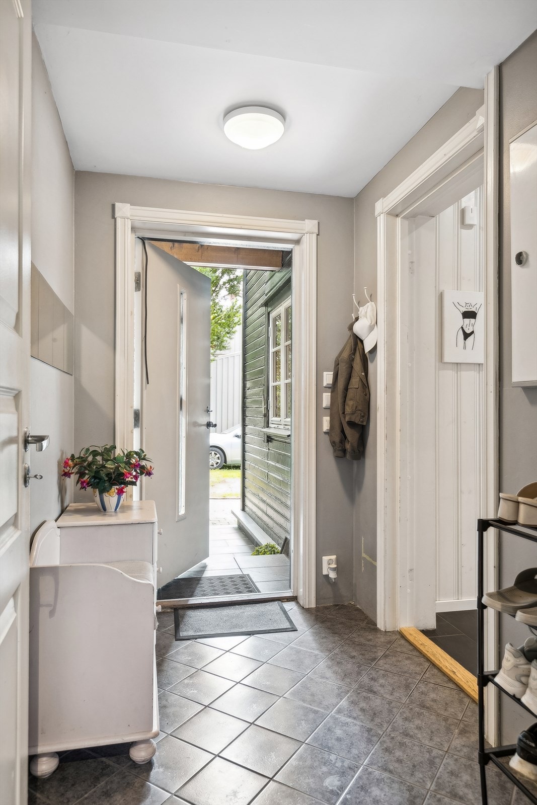 Flislagt entré med plass for knaggrekke, kommode/benk og skoparkering. Galleribilde
