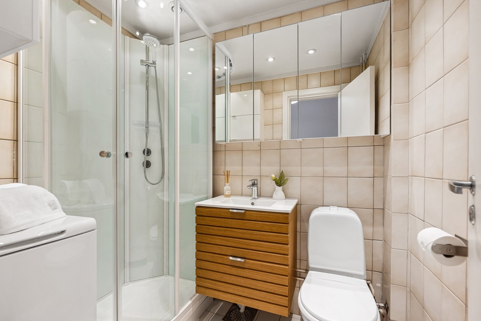 Baderommet er innredet med dusjkabinett og servant med undeskap og speilskap. Opplegg for vaskemaskin. Galleribilde