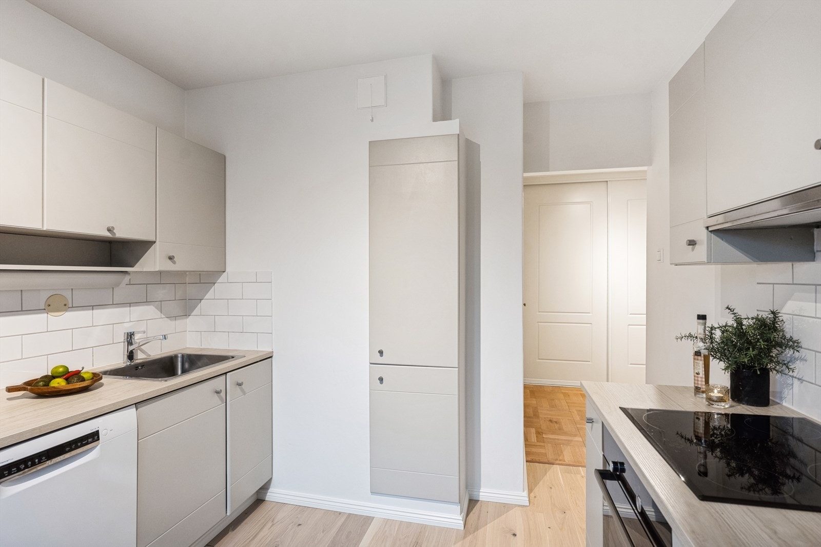 Kjøkkeninnredningen består av glatte fronter med fliser på vegg over benkeskap. Belysning under overskap. Laminat benkeplate med nedfelt kum i rustfritt stål. Stekeovn og platetopp er integrert i innredningen. Galleribilde