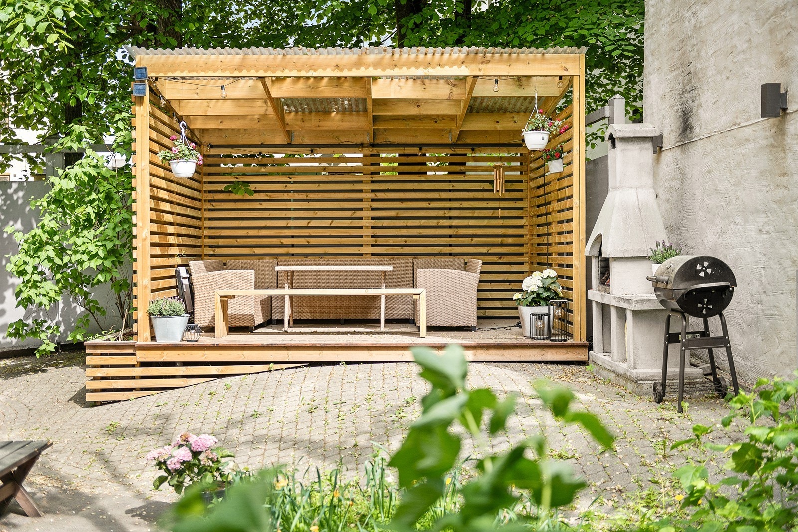 Bakgården er pent opparbeidet med pergola, grill og utepeis Galleribilde