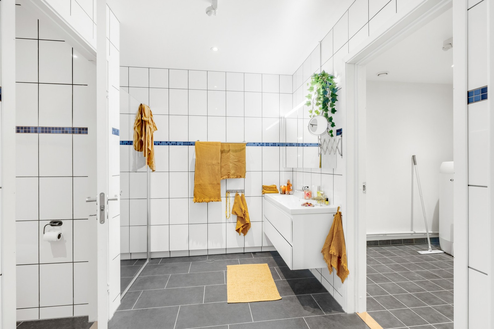 Romslig flislagt bad med dusjhjørne, vegghengt wc og baderomsinnredning. Galleribilde