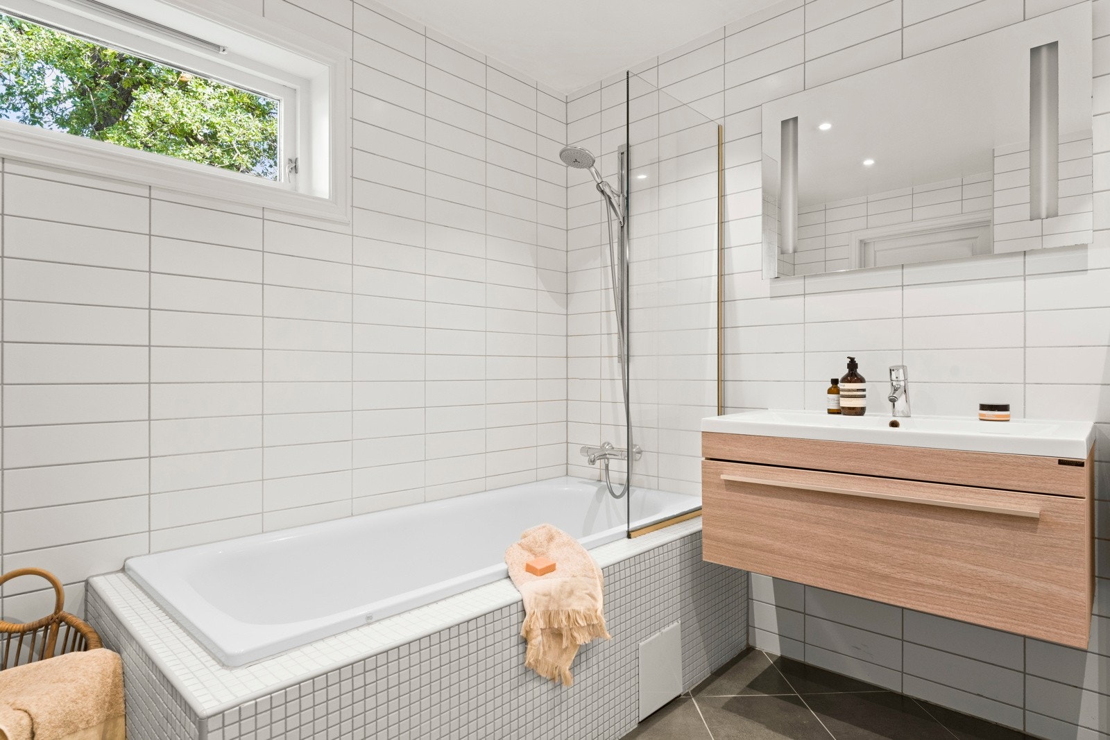 Nedfelt servant, veggmontert toalett og et innfliset badekar, samt opplegg for vaskemaskin. Galleribilde