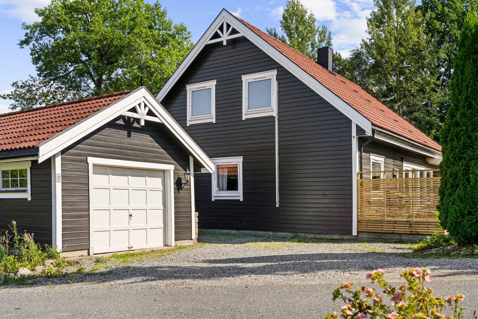 Tomten er opparbeidet med gruset innkjørsel, beplantning og gressplen. Galleribilde